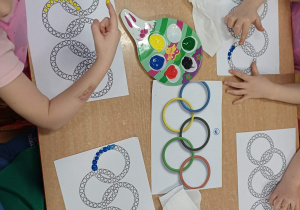 Wspólne tworzeznie przez dzieci symbolu olimpijskiego - kół w pięciu kolarach za pomocą stemplowania palcami kropek tworzących koła.