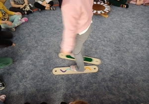 Próby chodzenia po klasie w imitacjach nart przez dzieci w środku elipsy.