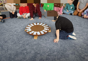 Kręcenie przez chłopca kołem fortuny z dyscyplinami zimowych igrzysk olimpijskich.