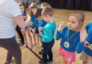 Dzieci otrzymujące symboliczne medale za uczestnictwo w zabawie.