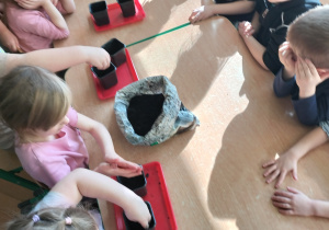 dzieci nabierają ziemię do doniczek