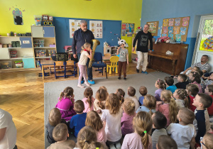 Dzieci siedzą na dywanie podczas koncertu.