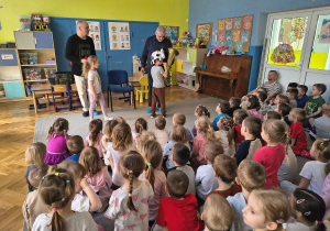 Dzieci siedzą na dywanie podczas koncertu.
