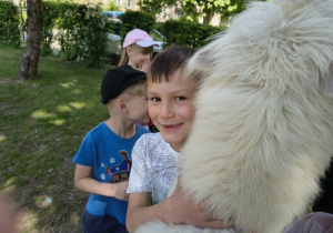 Chłopiec przytula się do białej alpaki.