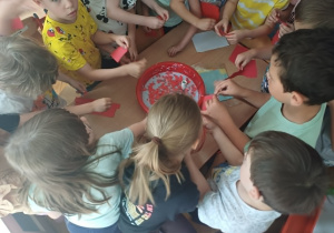 Dzieci dodają kolorowe kartki do powstałęj już pulpy papierowej.