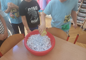 Zalewanie papierowych drobinek przez dzieci.