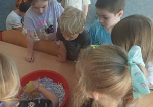 Dziei zajewają rozdrobniony papier wodą w misce.