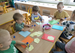 dzieci samodzielnie przyklejają elementy laurki