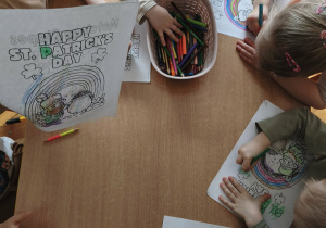dzieci siedzą przy stoliku i kolorują ilustracje