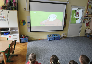 dzieci siedzą przy stoliku i kolorują ilustracje